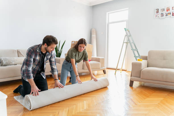 coppia srotolare tappeto in nuova casa - unrolling foto e immagini stock