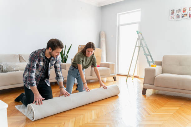 Couple unrolling carpet in new house