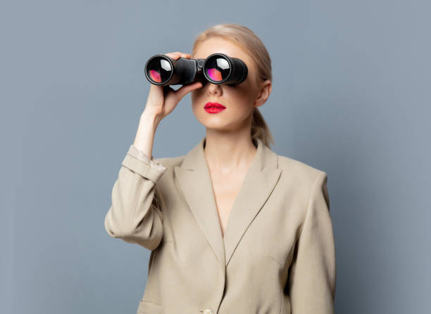 istock Style blonde in jacket with binoculars on gray background 1279710008