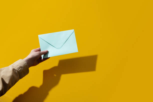 istock Woman hand holds blue envelope on yellow background 1279711003