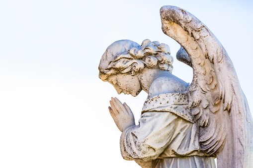 Little beautiful guardian angel statue in sunlight as a symbol of strength, truth and faith. Horizontal image.