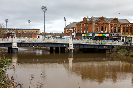 Taunton, Somerset - March 17th 2020: The Tone Bridge spanning over the River Tone in Taunton, Somerset. The floodlights of Somerset County Cricket Club can be seen in the background.