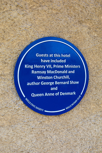 Wells, UK - March 16th 2020: A blue plaque on the exterior of the Swan Hotel in the city of Wells, detailing its former famous guests.