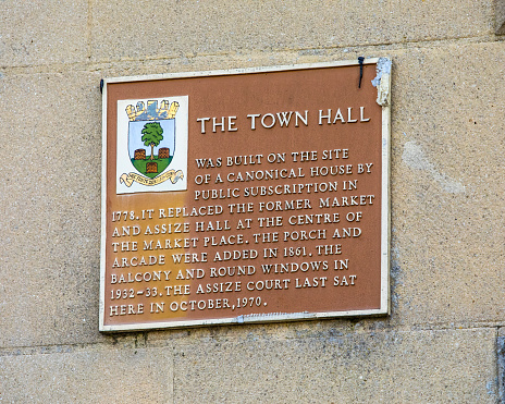 Wells, UK - March 16th 2020: Close-up of  a plaque on the exterior of the Town Hall in the city of Wells, detailing the history of the site.