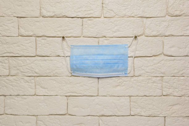 istock A blue medical mask hangs on a light brick wall in the center. 1279717170