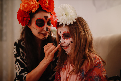 Mom putting makeup on her daughter for the Day of the dead celebration