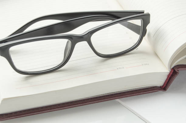 istock Stylish black reading glasses on an open diary, close-up banner 1279718485