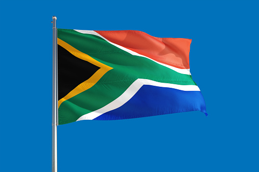 South Africa national flag waving in the wind on a deep blue sky. High quality fabric. International relations concept.