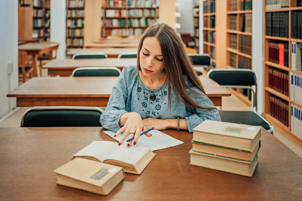istock Young woman studying in library 1279719090