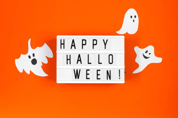 istock Halloween concept. Festive decorations - paper ghosts and spider web on orange background. 1279726692