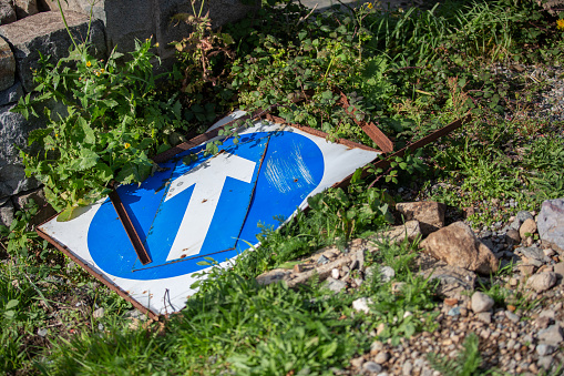 Old blue and white traffic sign with an arrow pointing dumped on the ground - mental health … life direction, route for life