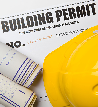 Building permit with hardhat and blueprints. Certificate was created by photographer with a graphics program. Code number is fictitious.