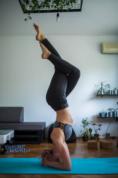 istock Woman practicing yoga and doing a headstand at home 1279747483
