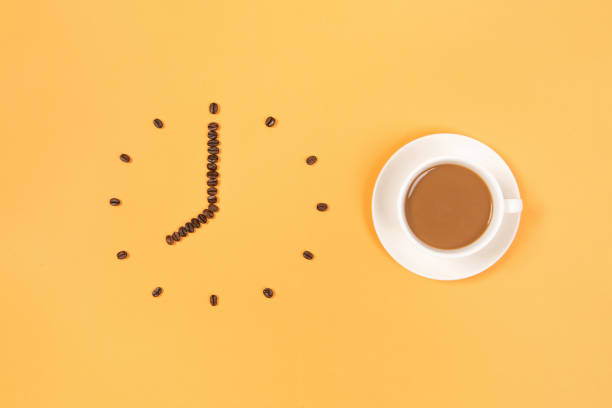 istock Coffee beans conventionalized to clock and a cup of coffee isolated on yellow background 1279754778