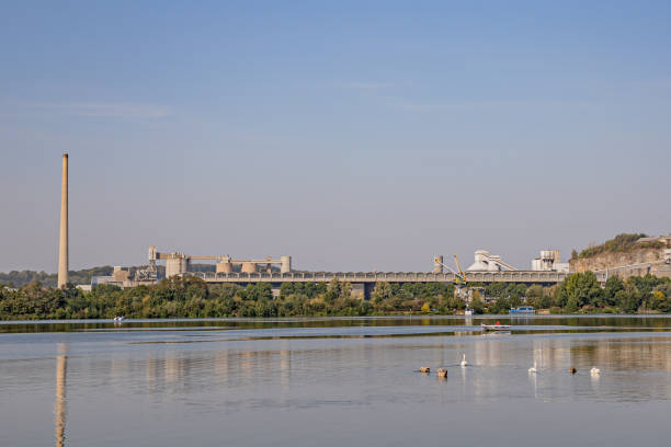 istock Maas River with slight reflection on its calm waters, swimming ducks and a small boat sailing with the old cement factory on the background 1279754977