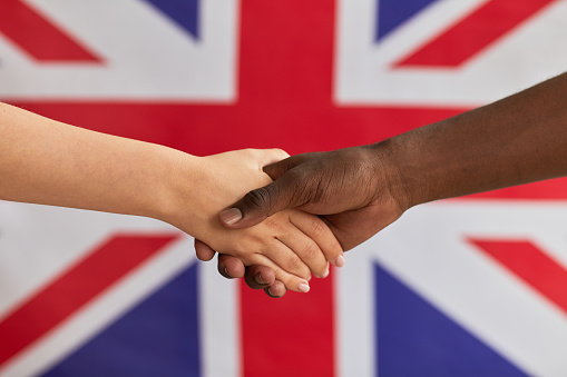 Close-up of people shaking hands against the British flag