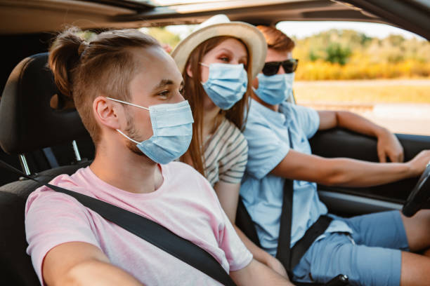 group of people riding in car with medical mask group of people riding in car with medical mask. coronavirus car rental covid stock pictures, royalty-free photos & images