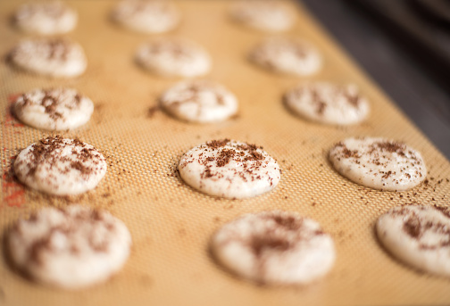 Close-up shot of cookies macrons on baking dish with sprinkled coffee