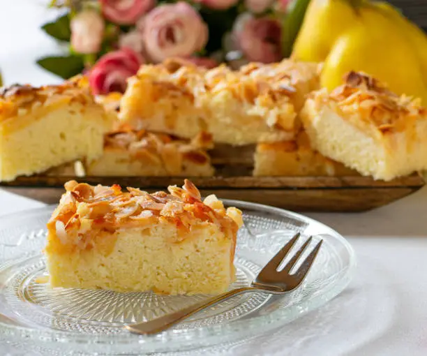Homeamde fresh almond cake with quinces - sheet cake - served on a plate with fork - ready to eat