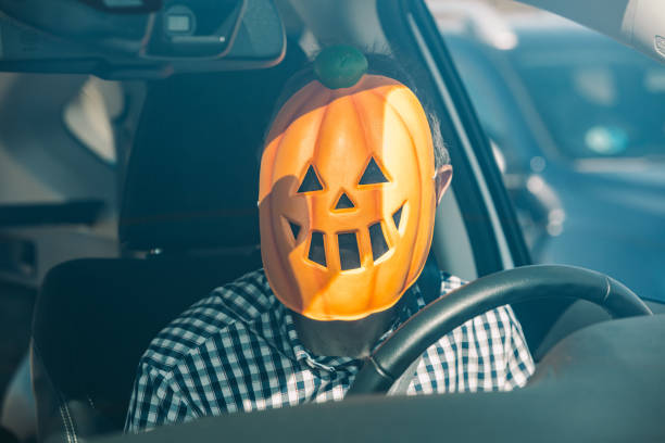 istock Man inside a car with a pumpkin mask of jack o lantern Hallowwen 1279761944