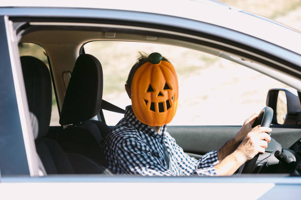 Man inside a car with a pumpkin mask of jack o lantern Hallowwen stock photo