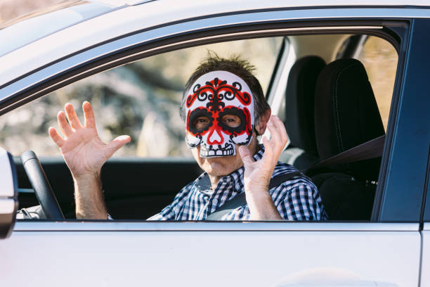 istock Man inside a car with a Hallowwen skull mask scaring 1279761967