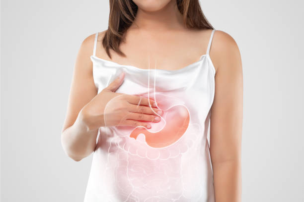 A woman suffering from gastroesophageal reflux disease A woman in white dress suffering from acid reflux or GERD on a light gray background, Gastroesophageal Reflux Disease, The concept of Medical treatment and Healthcare esophagus stock pictures, royalty-free photos & images