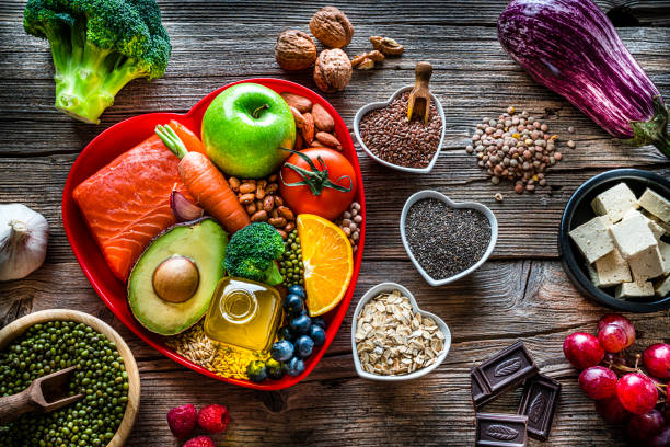alimentos saudáveis para menor colesterol e cuidados cardíacos em mesa de madeira - colesterol - fotografias e filmes do acervo