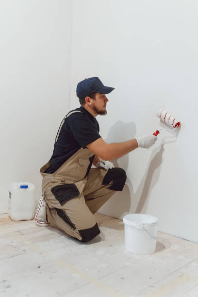 istock Handsome painter with paint roller in empty room paints the wall 1279764398