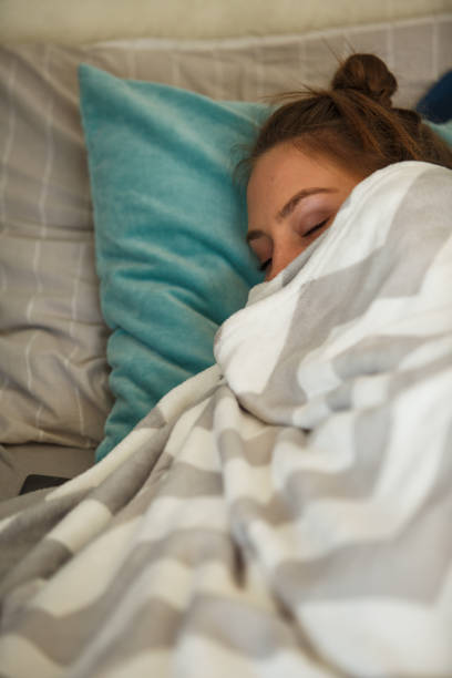 istock Young woman wrapped in blanket sleeping in her cozy bed 1279764536