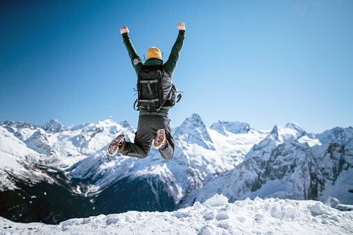 Cheerful man jumps in the air on top of the mountain