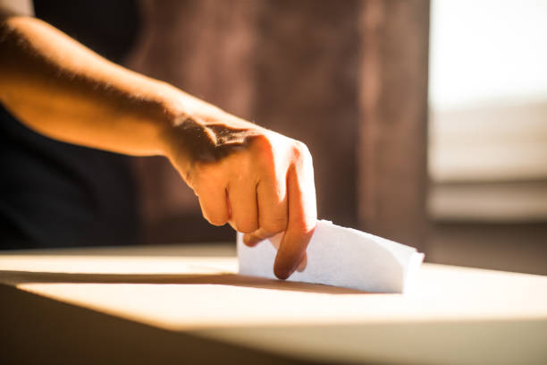 Conceptual image of a person voting, casting a ballot at a polling station, during elections.
