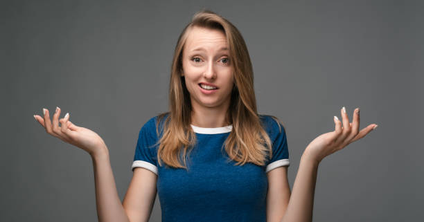 pretty girl shrugging shoulders over gray background. concept of doubt, uncertainty and confusion - blank expression head and shoulders horizontal studio shot imagens e fotografias de stock