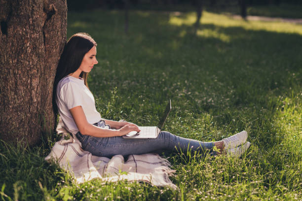 istock Profile side view portrait of her she nice attractive pretty focused cheery girl programmer sitting on lawn green grass veil duvet blanket working remotely writing e-mail creating presentation 1279769995