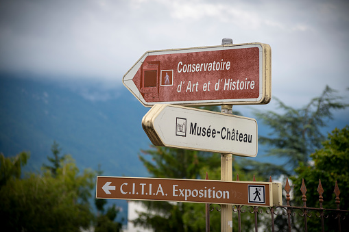 Direction signs for local attractions including a castle and an Art Gallery beside the lake in Annecy, France.