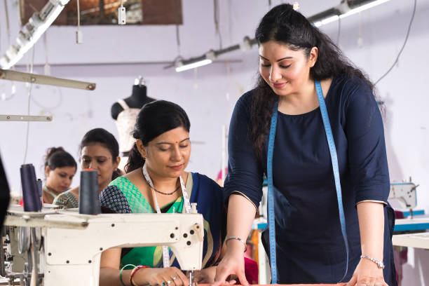 istock Instructor guiding female textile worker stitching garment on production line 1279774144