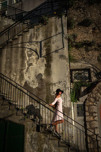 Beautiful woman in hard light with shadows of urban stairs and balustrade