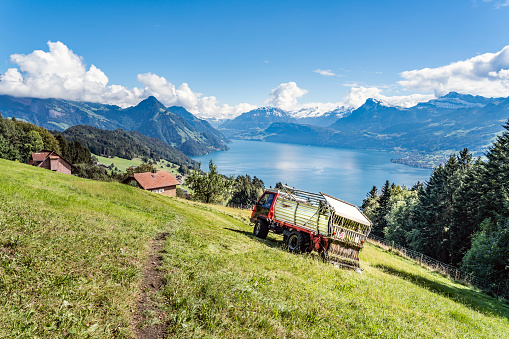 Agricultural vehicle during the hay harvest, Lake Lucerne and the Swiss Alps in the background, Switzerland