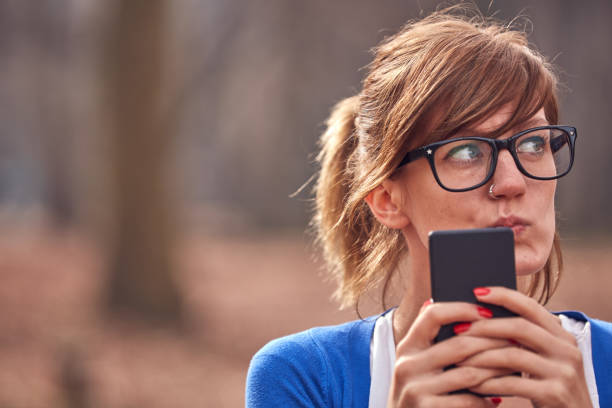 istock Young woman using smartphone in autumn colored park. 1279781541