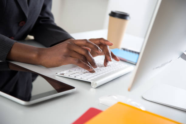 Close-up of hands of african-american businesswoman typing on a laptop. stock photo