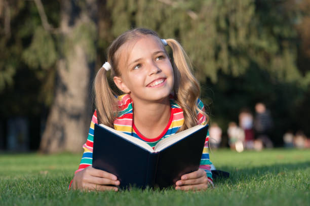 istock Cute pupil enjoy reading. School time. Developing caring learners who are actively growing and achieving. Little child reading book outdoors. Schoolgirl reading stories while relaxing green lawn 1279786328