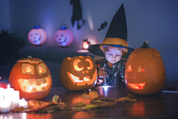 Child, toddler boy, playing with carved pumpkin at home on Halloween Child, toddler boy, playing with carved pumpkin at home on Halloween, making magic potion halloween pumpkin human face candlelight stock pictures, royalty-free photos & images