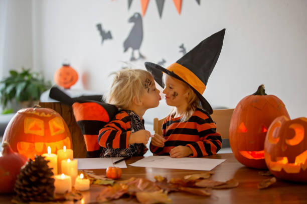 Children, toddler boy and girl, playing with carved pumpkin at home on Halloween Children, toddler boy and girl, playing with carved pumpkin at home on Halloween, making magic potion halloween pumpkin human face candlelight stock pictures, royalty-free photos & images