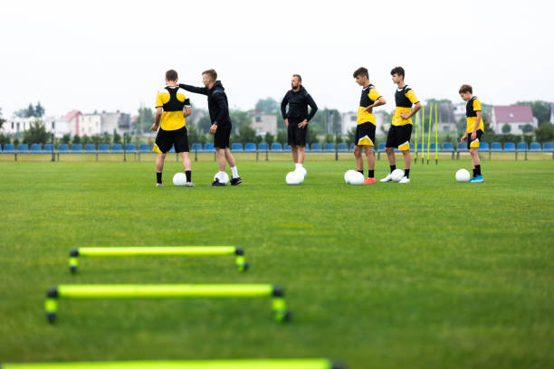 equipo de fútbol en entrenamiento. grupo de jóvenes jugadores de fútbol con entrenadores en el campo de práctica de hierba. entrenador joven explicando el plan de juego de entrenamiento al equipo - soccer ball youth soccer event soccer fotografías e imágenes de stock