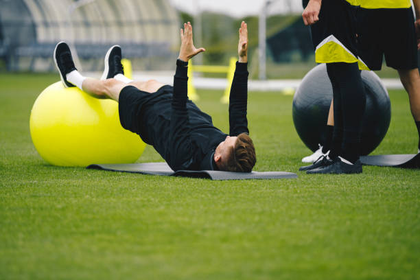 istock Young Coach Showing to Junior Players How to Exercise Properly on Training Mat and Training Yoga Ball. High Performance Sports Training For Youth Athletes 1279787591