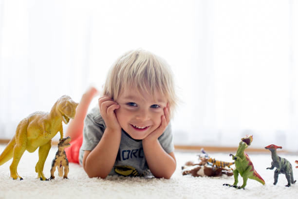 istock Blond toddler child, playing with dinosaurs at home 1279788958