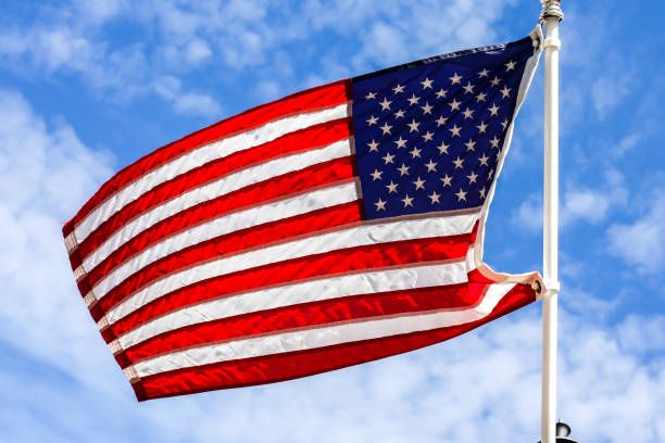 istock American flag with beautiful blue sky and white clouds 1279790558