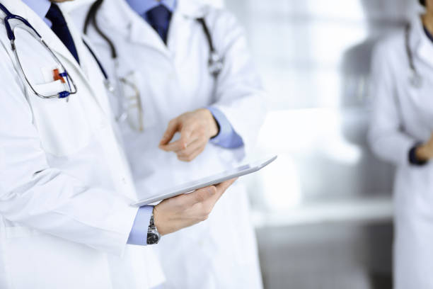 istock Group of unknown doctors use a computer tablet to check up some medical names records, while standing in a hospital office. Physicians ready to examine and help patients. Medical help, insurance in health care, best desease treatment and medicine concept 1279790824