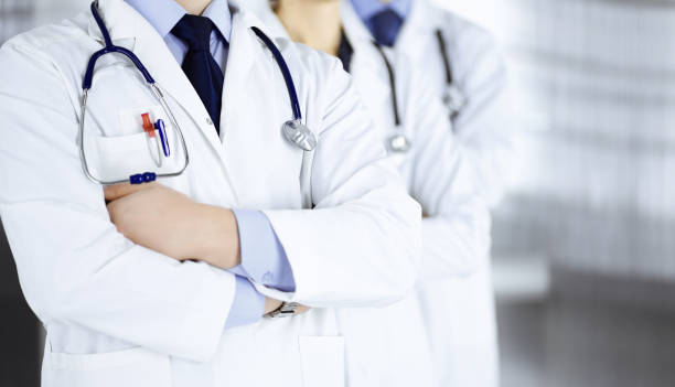Group of modern doctors standing as a team with crossed arms and stethoscopes in hospital office. Physicians ready to examine and help patients. Medical help, insurance in health care, best desease treatment and medicine concept. grupo de médicos modernos de pie como un equipo con brazos cruzados y estetoscopios en la oficina del hospital. médicos listos para examinar y ayudar a los pacientes. ayuda médica, seguro en atención médica, mejor tratamiento desease y concepto de med