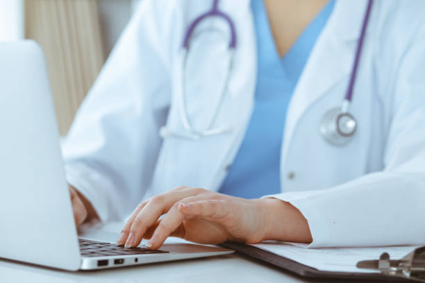 istock Unknown woman-doctor typing on laptop computer while sitting at the table. Medicine concept 1279792063